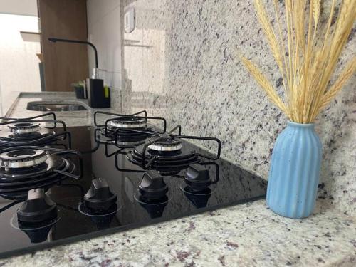 a kitchen counter with a stove with a blue vase at Apartamento próximo a uopeccan in Umuarama