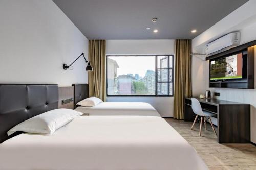 a bedroom with three beds and a desk and a tv at Hi Inn Hangzhou Sijiqing Qiutao North Road in Hangzhou