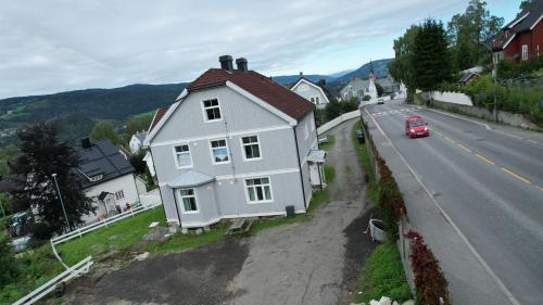 a white house on the side of a road with a red car at Sentrumsnær leilighet - K1 in Lillehammer