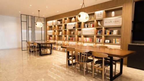 a dining room with a book shelf and a table and chairs at Hanting Hotel Xiamen University in Xiamen