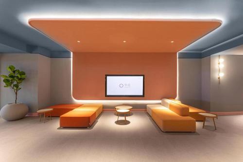 a living room with orange furniture and a flat screen tv at Hanting Hotel Nanjing Garden City Maihua Road in Yen-tzu-chi