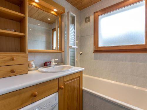 La salle de bains est pourvue d'un lavabo, d'une baignoire et d'une fenêtre. dans l'établissement 3* Calme, ensoleillé, garage, balcon, cheminée - FR-1-304-193, à La Clusaz