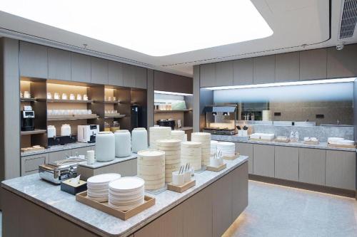 a large kitchen with white dishes on a counter at Ji Hotel Dandong Railway Station in Dandong