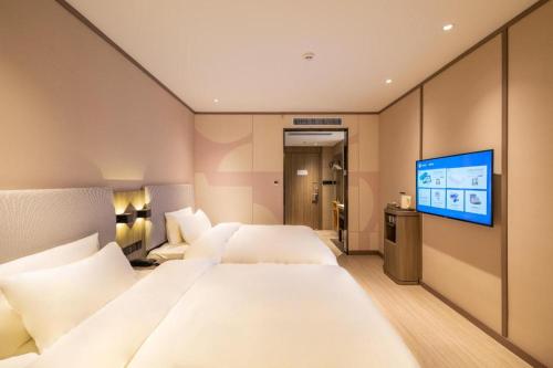 a hotel room with two beds and a flat screen tv at Hanting Hotel Lingbao Municipal Government in Lingbao