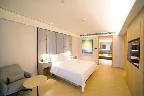 a bedroom with a white bed and a chair at Ji Hotel Guangzhou Baiyun Airport in Huadu