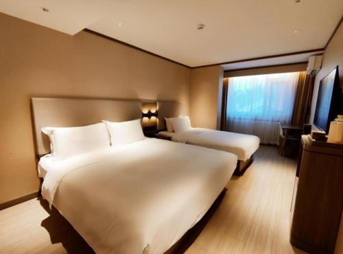 Cette chambre comprend 2 lits et une fenêtre. dans l'établissement Hanting Hotel Qingdao Nanjing Road, à Fushansuo