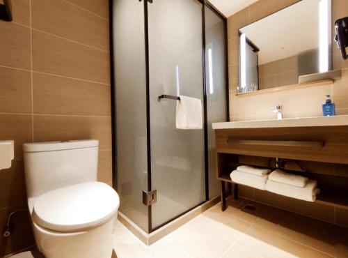 La salle de bains est pourvue de toilettes, d'une douche et d'un lavabo. dans l'établissement Hanting Hotel Qingdao Nanjing Road, à Fushansuo