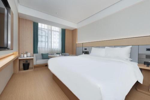 a large white bed in a hotel room at Ji Hotel Wuhan Jiedaokou in Han-yang-hsien
