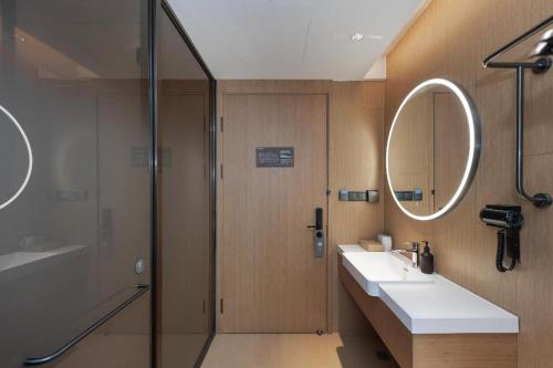 a bathroom with a shower and a sink and a mirror at Ji Hotel Wuhan Jiedaokou in Han-yang-hsien