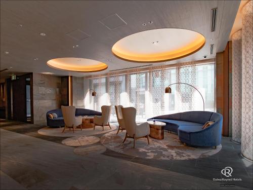 a lobby with blue couches and chairs and windows at Daiwa Roynet Hotel Osaka Sakaisuji Honmachi PREMIER in Osaka