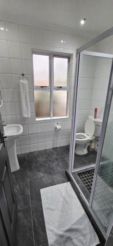a bathroom with a shower with a toilet and a sink at Luxe Florida Grand Hotel in Durban