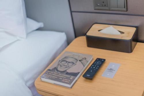 a bedside table with a remote control and a book at Ji Hotel Xuzhou Administrative Center Metro Station in Liuji