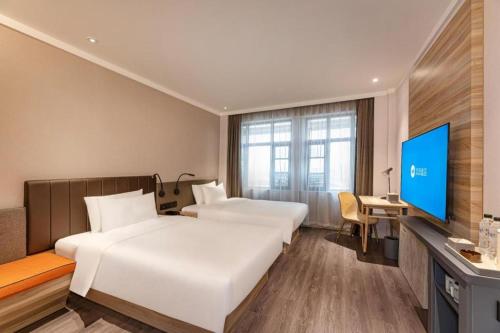 JiangduにあるHanting Hotel Yangzhou Jiangdu Wenchang East Roadのベッド2台、薄型テレビが備わるホテルルームです。