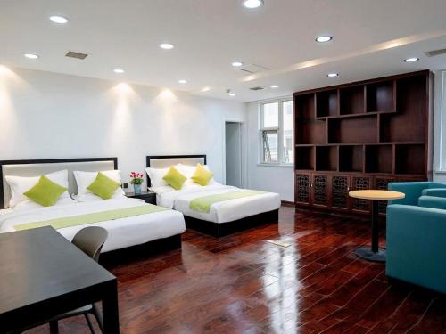 Zimmer mit 2 Betten, einem Tisch und einem Sofa in der Unterkunft Hi Inn Qinhuangdao Railway Station in Qianmafang