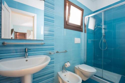 a blue bathroom with a sink and a toilet at Village Baia Turchese in Vieste