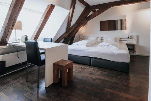 um quarto com uma cama, uma secretária e uma mesa em Design Hotel & Restaurant Löwen em Ulm