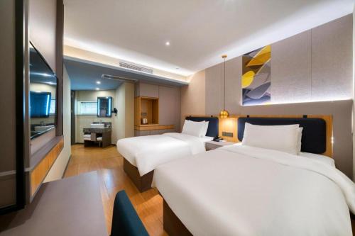a hotel room with two beds and a television at Hanting Hotel Hangzhou Zhejiang University City College in Hangzhou
