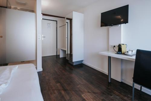 a room with a bed and a desk and a tv at Design Hotel & Restaurant Löwen in Ulm