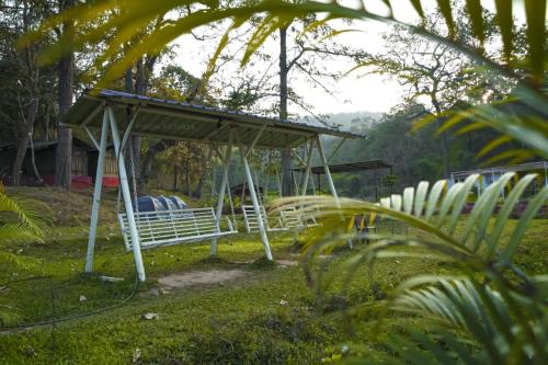 a park bench with a canopy in the grass at Dandeli Hidden Valley by StayApart in Ganeshgudi