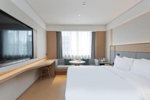 a hotel room with a bed and a flat screen tv at Ji Hotel Wuhan Yellow Crane Tower Shouyi Road in Han-yang-hsien