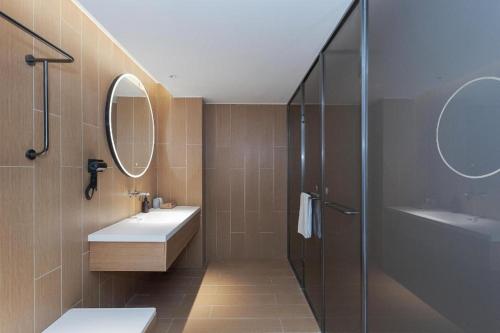 a bathroom with a sink and a shower and a mirror at Ji Hotel Wuhan Yellow Crane Tower Shouyi Road in Han-yang-hsien