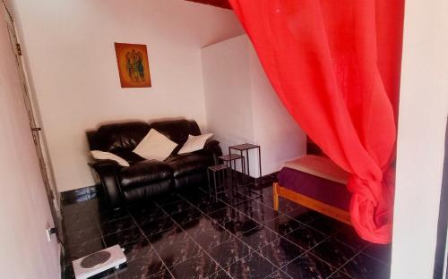 uma sala de estar com cadeiras de couro preto e uma cortina vermelha em KAIRO em Brufut