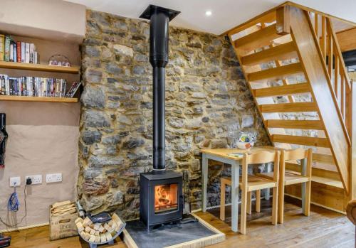 a wood stove in a living room with a stone wall at Stable Cottage in Pembroke