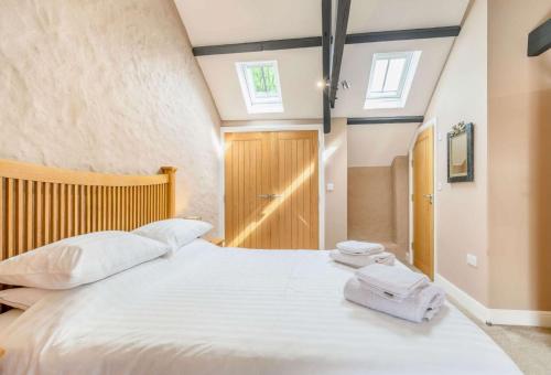 a bedroom with a large white bed with towels on it at Stable Cottage in Pembroke