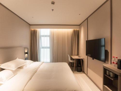 a hotel room with a large bed and a flat screen tv at Hanting Hotel Shanghai Qingpu Huijin Road Metro Station in Qingpu