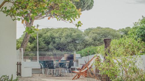 een patio met een tafel en stoelen en een boom bij Pine House - Faro Airport, Beach and City Center in Faro