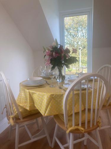 a table with a yellow table cloth and a vase of flowers on it at The Old Milk House in Richmond