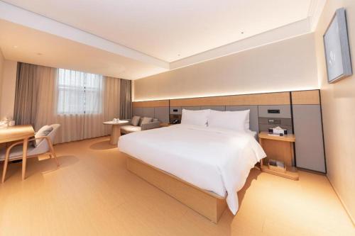 a hotel room with a large bed and a desk at Ji Hotel Nanjing Xianlin Wandamao in Dongchanglin