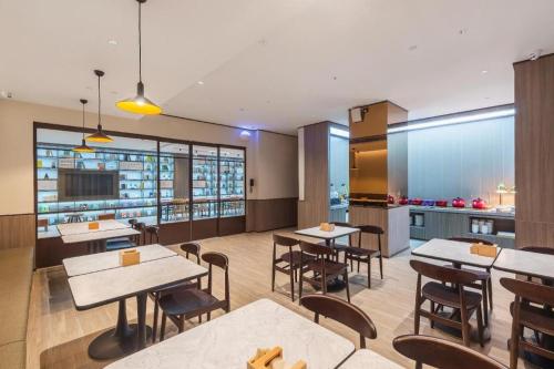 een restaurant met tafels en stoelen en een keuken bij Hanting Hotel Jinan Beiyuan Street Ouyada in Licheng