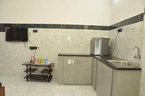 a small kitchen with a sink and a microwave at Roof-top stay in centre of city in Thanjāvūr