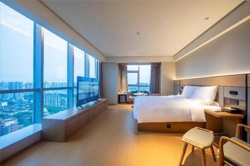 a bedroom with a large bed and large windows at Ji Hotel Changde Hunan Wenli College in Changde