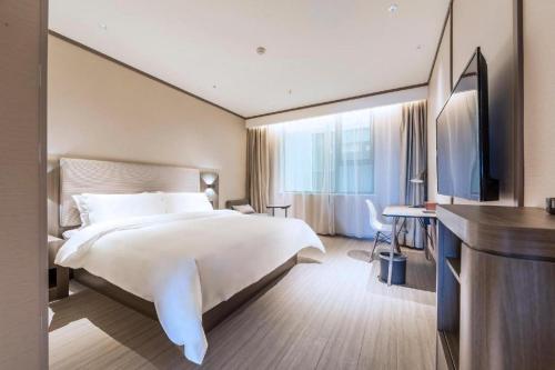 Un pat sau paturi într-o cameră la Hanting Hotel Zhengzhou South Longhu Shawoli Metro Station