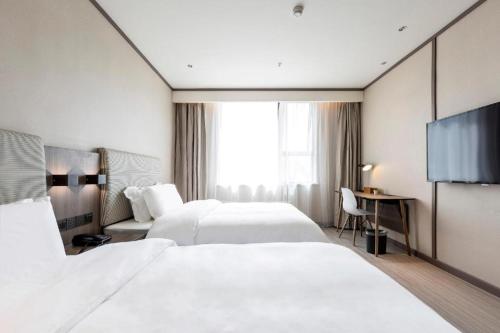 a hotel room with two beds and a tv at Hanting Hotel Zhengzhou South Longhu Shawoli Metro Station in Guodian