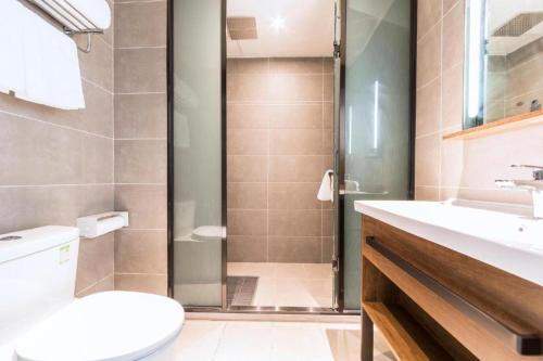 a bathroom with a shower and a toilet and a sink at Hanting Hotel Zhengzhou South Longhu Shawoli Metro Station in Guodian