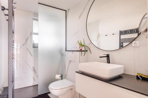 une salle de bain blanche avec un lavabo et un miroir dans l'établissement Appartement Marina Baie des Anges, à Villeneuve-Loubet