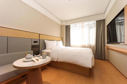 a hotel room with a bed and a table at Ji Hotel Shanghai Xujiahui Guanshengyuan Road in Shanghai