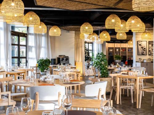 un restaurante con mesas, sillas y lámparas de araña en Mercure Cannes Mandelieu, en Cannes