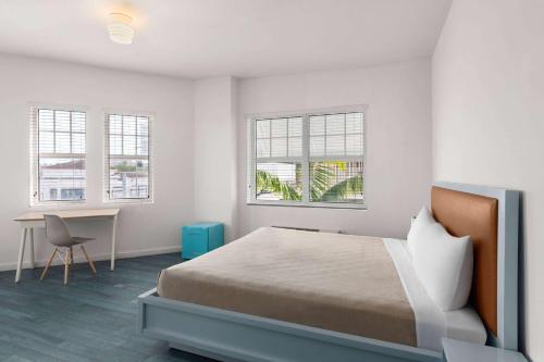 a bedroom with a bed and a desk and windows at The Variety by LuxUrban in Miami Beach