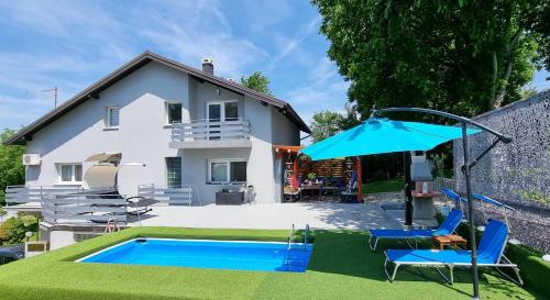 a house with a swimming pool and a blue umbrella at Apartmani Habibi in Jalžabet