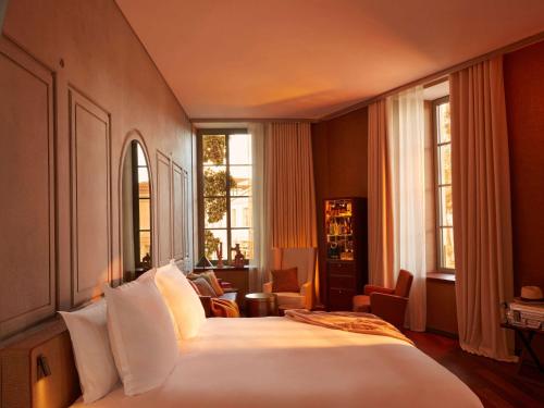 - une chambre avec un grand lit blanc et des fenêtres dans l'établissement Mondrian Bordeaux Les Carmes, à Bordeaux