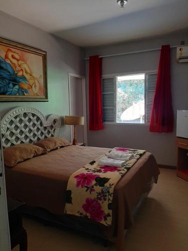 a bedroom with a bed and a window with red curtains at Pousada e Museu JK in Ubajara