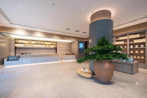 a large lobby with a potted plant in the middle at Ji Hotel Shenyang Zhong Street Gugong in Shenyang