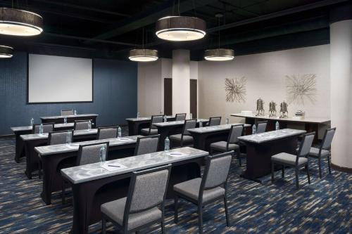 a conference room with tables and chairs and a screen at DoubleTree by Hilton Charlotte City Center in Charlotte