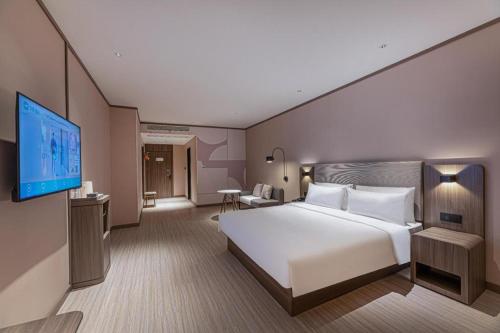 een hotelkamer met een bed en een flatscreen-tv bij Hanting Hotel Taizhou Jiangyan Pedestrian Street in Guanzhuang