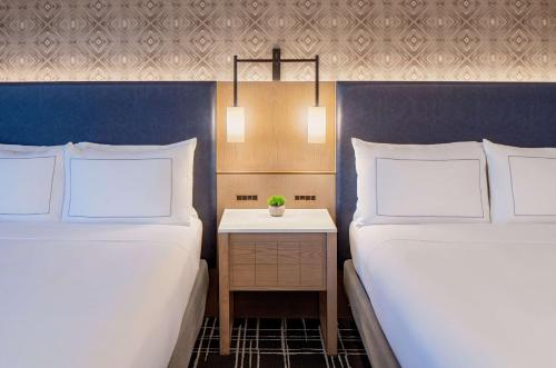 a bedroom with two beds and a nightstand between them at Doubletree Suites by Hilton Salt Lake City in Salt Lake City