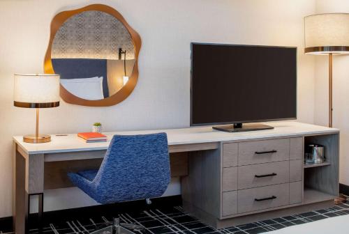 a desk with a television and a blue chair at Doubletree Suites by Hilton Salt Lake City in Salt Lake City